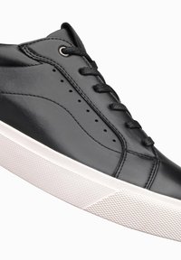 Baskets en cuir noir avec une texture lisse, dotées de six œillets, de lacets noirs et d'une semelle en caoutchouc blanc avec un motif texturé.