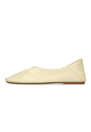 Chaussure plate en cuir couleur crème avec un bout arrondi et une semelle basse marron vue de côté.