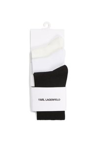 Tre par ankelstrømper i hvid, off-white og sort, pakket med et hvidt bånd mærket "Karl Lagerfeld."