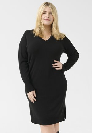 Schwarzes Strickkleid mit V-Ausschnitt, langen Ärmeln und seitlichen Schlitzen. Das Material wirkt dehnbar und weich, ideal für legere Outfits.