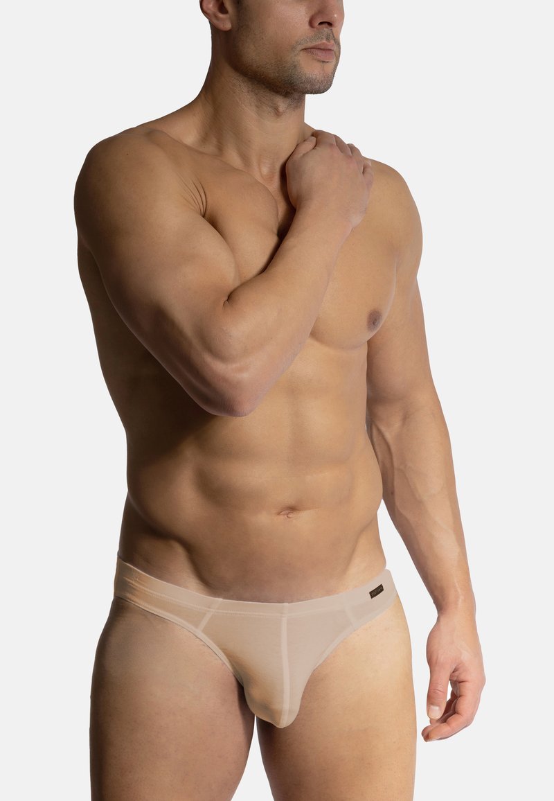 Béžové pánské trenýrky vyrobené z průhledné tkaniny, s nízkým pasem a jemnými švy, které zvýrazňují kontury těla.
