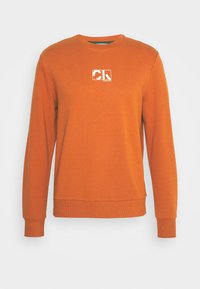 Sudadera naranja con cuello redondo fabricada en algodón suave. Presenta un logo blanco en el pecho y puños y dobladillo acanalados para un ajuste ceñido.