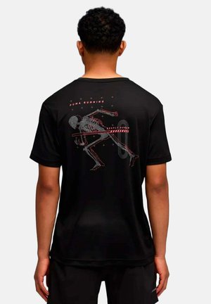 Mann trägt schwarzes Puma Running Shirt mit einer Grafik des Skeletts eines Läufers und Text auf der Rückseite.
