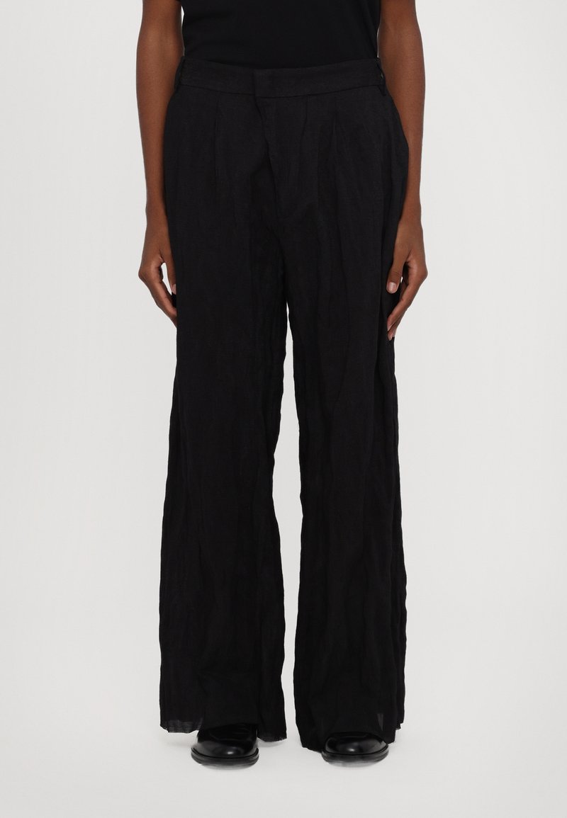 Pantalones plisados negros hechos de una tela texturizada, con un diseño de pierna ancha y una cinturilla suave.