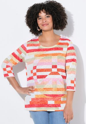 Chemise multicolore avec des rayures rouges, oranges et jaunes, présentant un motif de signe de paix. Le tissu est léger et possède une texture douce.