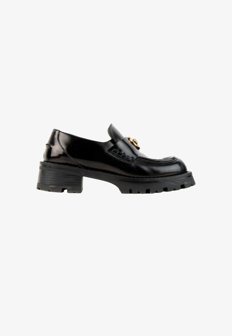 Mocassin en cuir noir avec semelle épaisse et talon bloc, avec une boucle décorative dorée sur la bride supérieure.