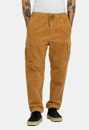 Cordhose in Kamelbraun mit zwei Seiten- taschen, elastischem Bund mit Tunnelzug und lockerer Passform. Strukturierte Oberfläche.