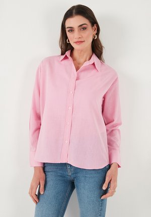Camicetta button-up rosa chiaro con maniche lunghe, colletto a punta e orlo leggermente arrotondato. Realizzata in un tessuto morbido e textured.