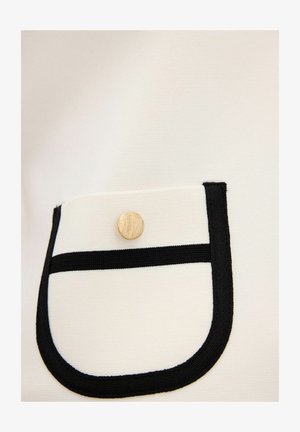 Weißer Stoff mit texturierten Oberfläche, der über eine schwarz eingefasste Tasche und einen metallisch goldenen Knopfakzent verfügt.