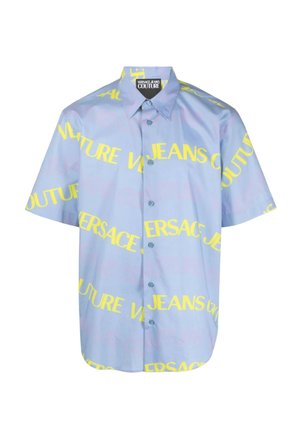 Camicia a maniche corte con bottoni in tessuto azzurro chiaro, con il testo audace giallo "VERSACE JEANS COUTURE" in varie orientazioni.