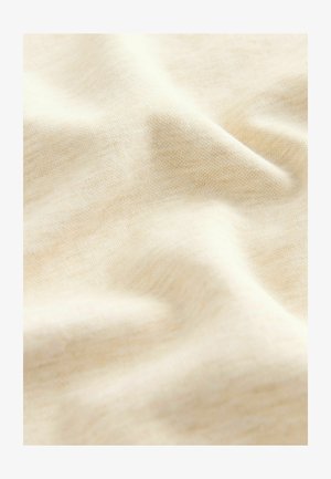 Crèmegekleurde stof met een zachte textuur, die een licht geweven patroon bevat, valt soepel en benadrukt de lichte kwaliteit.