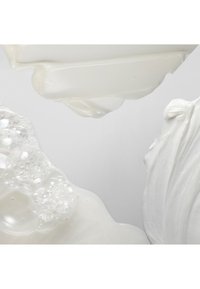 Drie texturen van witte crème, waaronder een glanzende, gladde laag, een dikke, glanzende lint en een luchtig, transparant gebied met reflecties.