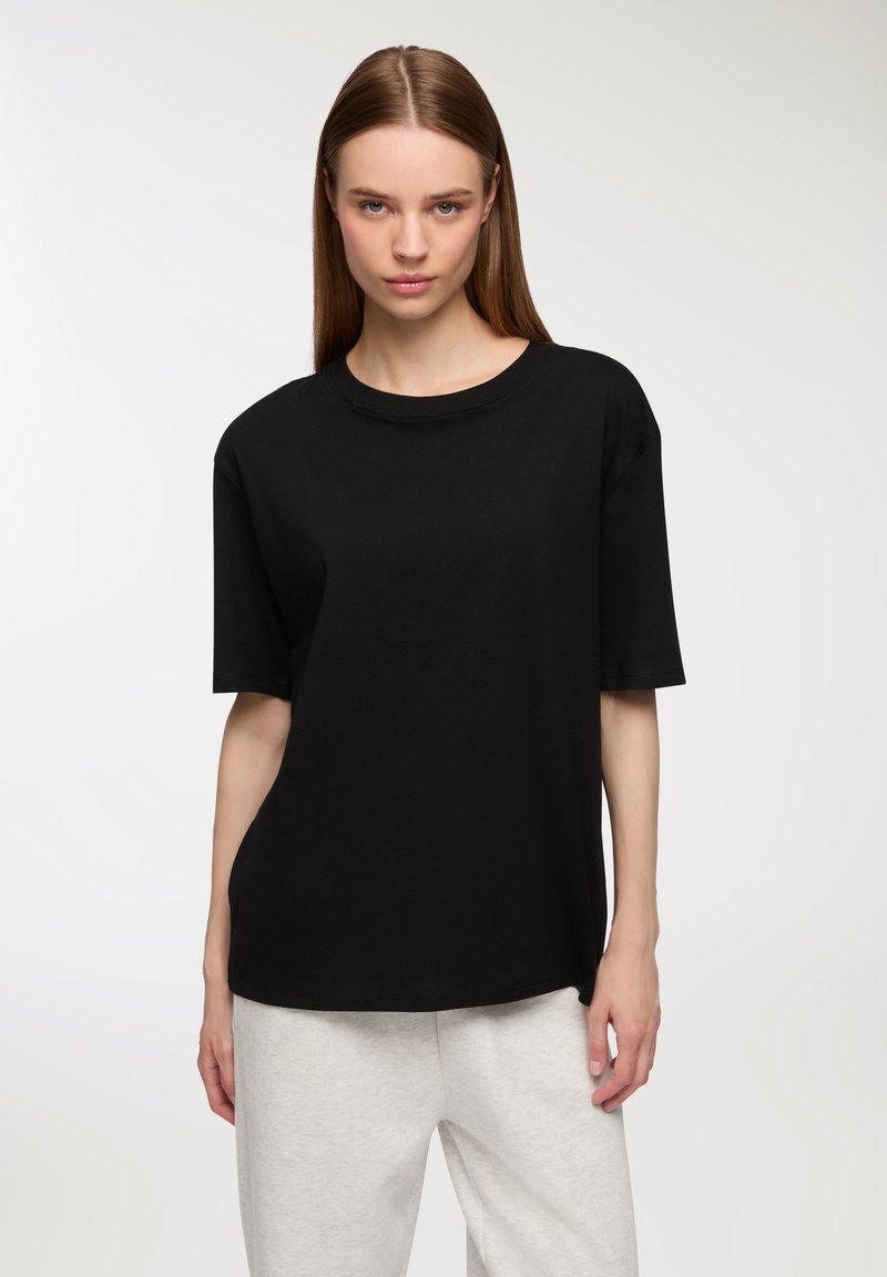 Czarna bawełniana koszulka z krótkim rękawem, okrągłym dekoltem, luźnym krojem, gładką teksturą i bez widocznych wzorów lub akcentów.