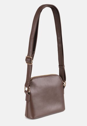 Sac bandoulière en cuir marron avec une bandoulière réglable et une fermeture éclair dorée, présenté sur un fond blanc uni.