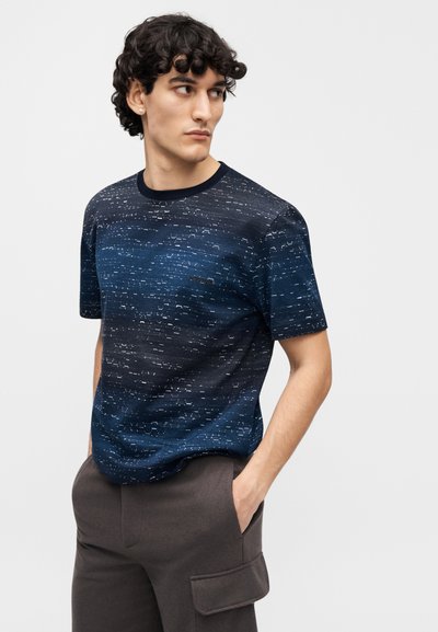 Short-sleeve navy blue t-shirt featuring a textured pattern with lighter accents. Crew neck design, paired with dark trousers.
