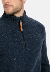 Granatowy sweter z dzianiny z wysokim kołnierzem, z zamkiem błyskawicznym, skórzaną zawleczką i teksturowanym, nakrapianym wzorem.