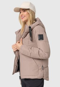 Polstret beige jakke med hætte, frontlynlås og elastiske manchetter. Har et sort logo-patch på venstre ærme og en glat overflade.