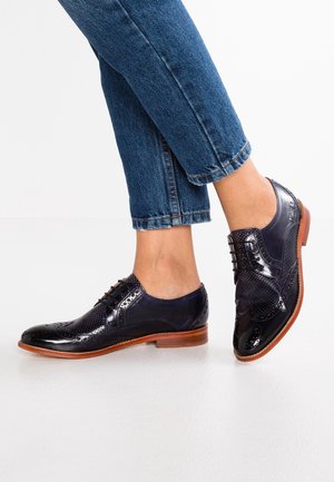 Marineblauwe leren brogues met perforaties op de neus en zijkanten, een bruine houten zool en een ronde vorm.