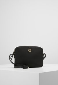 Borsa a tracolla nera in nylon con logo dorato, chiusura con zip e tracolla regolabile. Presenta una forma rettangolare e una texture liscia.