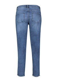Jean en denim bleu vu de dos avec deux poches arrière, une ceinture avec passants de ceinture et des ourlets effilochés aux ouvertures des jambes.