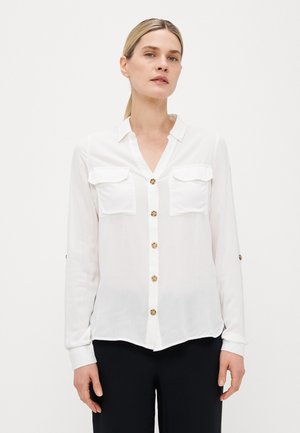 White button-up shirt with two chest pockets, gold-tone buttons, long sleeves, and a slightly curved hem. Smooth, lightweight fabric.