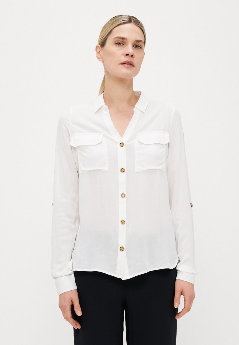 Witte button-up shirt met twee borstzakken, goudkleurige knopen, lange mouwen en een licht gebogen zoom. Glad, lichtgewicht materiaal.