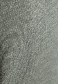 Lichtgrijze textuurstof met een gebreid patroon, die een gladde oppervlakte toont met subtiele variaties in tint.