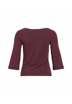 Tumši sarkana sieviešu garroku blūze ar laivu kakla izgriezumu un piegulošu siluetu, redzama no aizmugures uz baltas beigām.