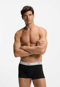 Boxer in stoffa nera con elastico grigio con la scritta "BOSS". Realizzati in tessuto morbido, presentano una vestibilità aderente e una texture liscia.