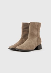 Semsket ankelstøvletter i beige med firkantet tå, middels høy blokkhel og sømløs design. Teksturert finish gir visuelt dybde.