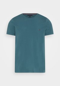 Tyrkysové bavlněné tričko s krátkým rukávem a kulatým výstřihem, které má na hrudi malé vyšívané logo. Hladká textura s klasickým střihem.