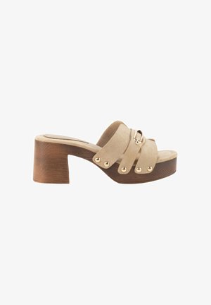Mule beige de ante con puntera abierta, tachuelas doradas, cadena decorativa y tacón bloque de madera.