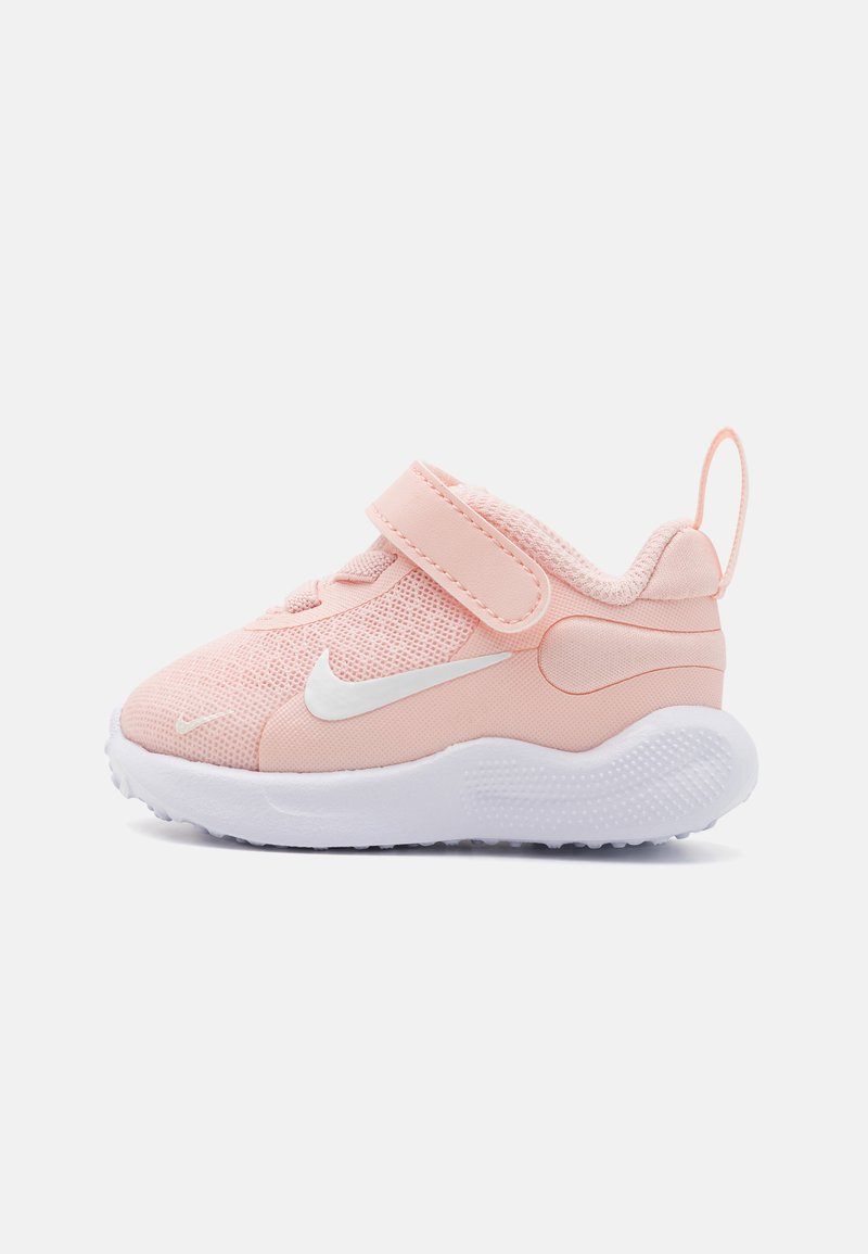 Baskets de sport roses avec tige en mesh, swoosh blanc, bande Velcro et semelle blanche texturée. Bout arrondi et tirette au talon.