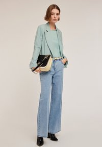 Vihreä bleiseri yhteensopivan topin päällä, yhdistettynä leveälahkeisiin sinisiin farkkuihin. Kaksivärinen käsilaukku mustalla ja kermaisen valkoisella. Mustat korkokengät.