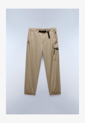 Beige, leichte Stoffhosen mit elastischem Bund, verstellbarem Gürtel, mehreren Taschen und schmal zulaufenden Beinen. Mit einer seitlichen Cargo-Tasche.