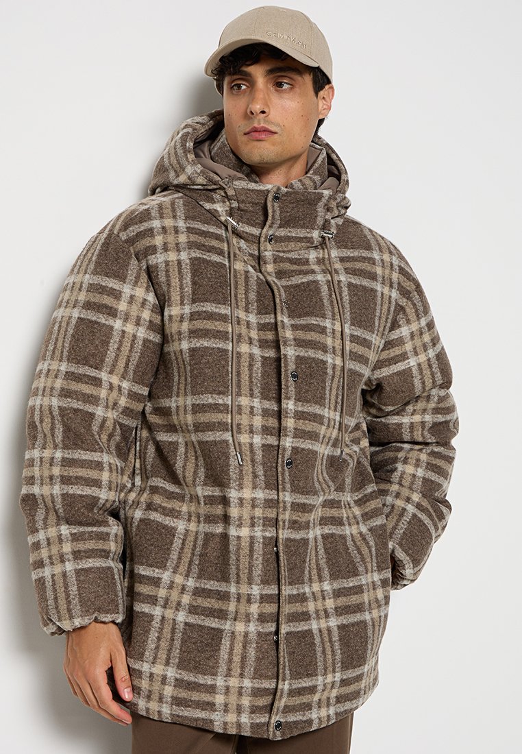 Veste à capuche surdimensionnée en plaid marron et beige, avec une texture en polaire, des boutons à l'avant et des cordons de serrage ajustables au col.