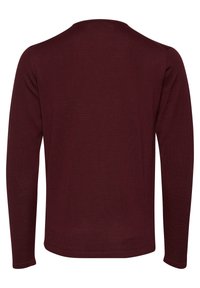 Langermet plagg i bordeaux, laget av mykt, strukturert stoff. Har rund hals og tettsittende mansjetter. Mangler synlige logoer eller mønstre.
