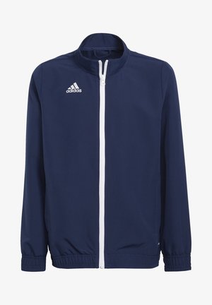 Giacca blu navy con colletto alto, zip bianca e polsini elastici. Presenta il logo Adidas ricamato in bianco sul lato sinistro del petto.