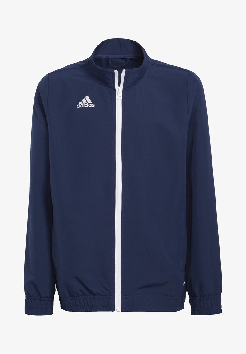 Marineblaue Jacke mit hohem Kragen, weißem Reißverschluss und elastischen Bündchen. Mit dem in Weiß gestickten Adidas-Logo auf der linken Brust.
