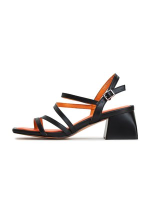 Sandal de cuero negro con múltiples correas ajustables, con un forro interior naranja y un modesto tacón cuadrado.