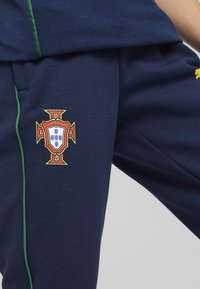 Mornarske sportske hlače s zelenom prugom, s grbom portugalske nogometne reprezentacije izvezenim na lijevom bedru.