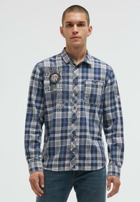 Blau- und grau karierter Flanellshirt mit Knopfleiste, schwarzen gestickten Akzenten, Brusttasche und langen Ärmeln.