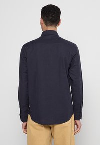 Marineblauw overhemd met lange mouwen van katoen, voorzien van een button-down kraag, een afgeronde zoom en manchetten met één knop.