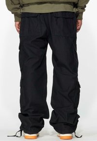 Black cargo pants with multiple side pockets, elastic cuffs, and a relaxed fit. Material appears lightweight with a matte texture.
