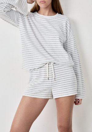 Ensemble de vêtements de détente rayé blanc et gris comprenant un haut à manches longues et un short assorti, fabriqué en tissu doux et texturé avec une taille élastique à cordon.