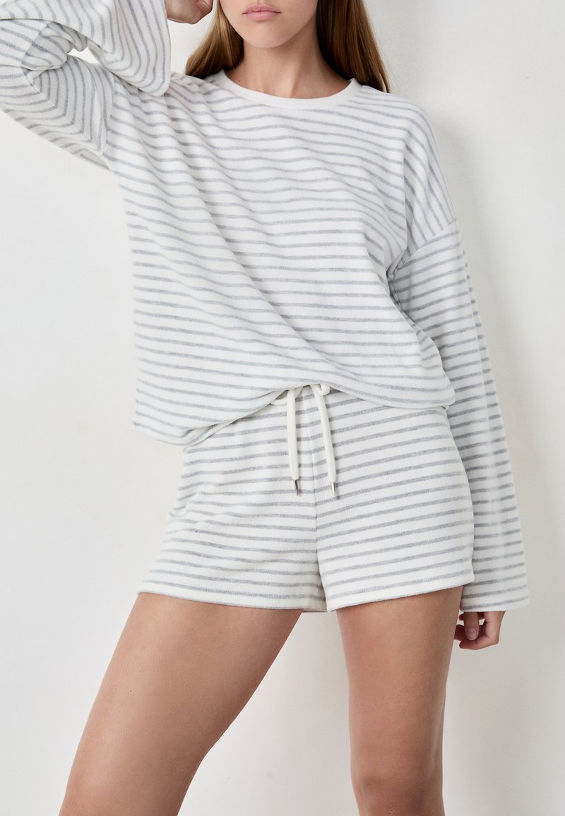 Biały i szary pasowany zestaw dresowy składający się z długiego rękawa i dopasowanych szortów, wykonany z miękkiego, teksturowanego materiału z wiązanym paskiem w talii.