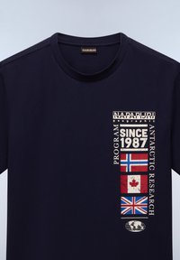 Navy blå bomulds t-shirt med rund hals, der har grafiske tryk af flag, textelementer og et globuslogo på forsiden.