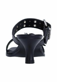 Sandale à talon haut en cuir noir avec un bout rond, une sangle à l'arrière, des clous sur la bande de cheville et un talon fin. Texture lisse et design minimal.