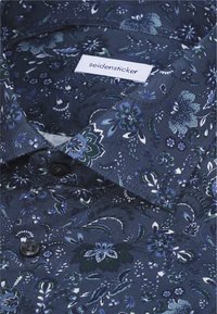 Chemise bleu foncé à boutons avec un motif floral dans des tons de bleu et blanc, avec une étiquette de marque "seidensticker" à l'intérieur du col.