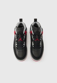 Melni sporta apavi no zamša un ādas materiāliem; ar sarkaniem akcentiem, pelēkām detaļām un teksturētu gumijas zolīti. Ar šņorēm.